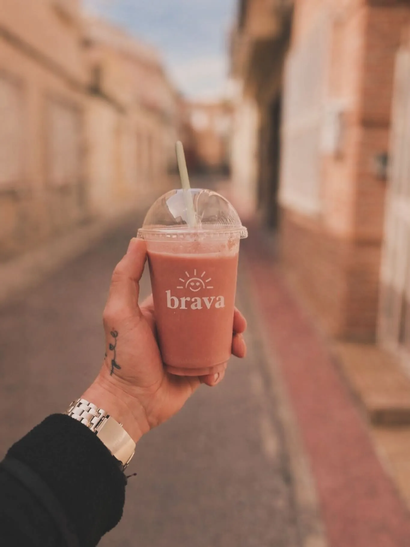 Smoothie Brava en vaso para llevar, sostenido en la calle