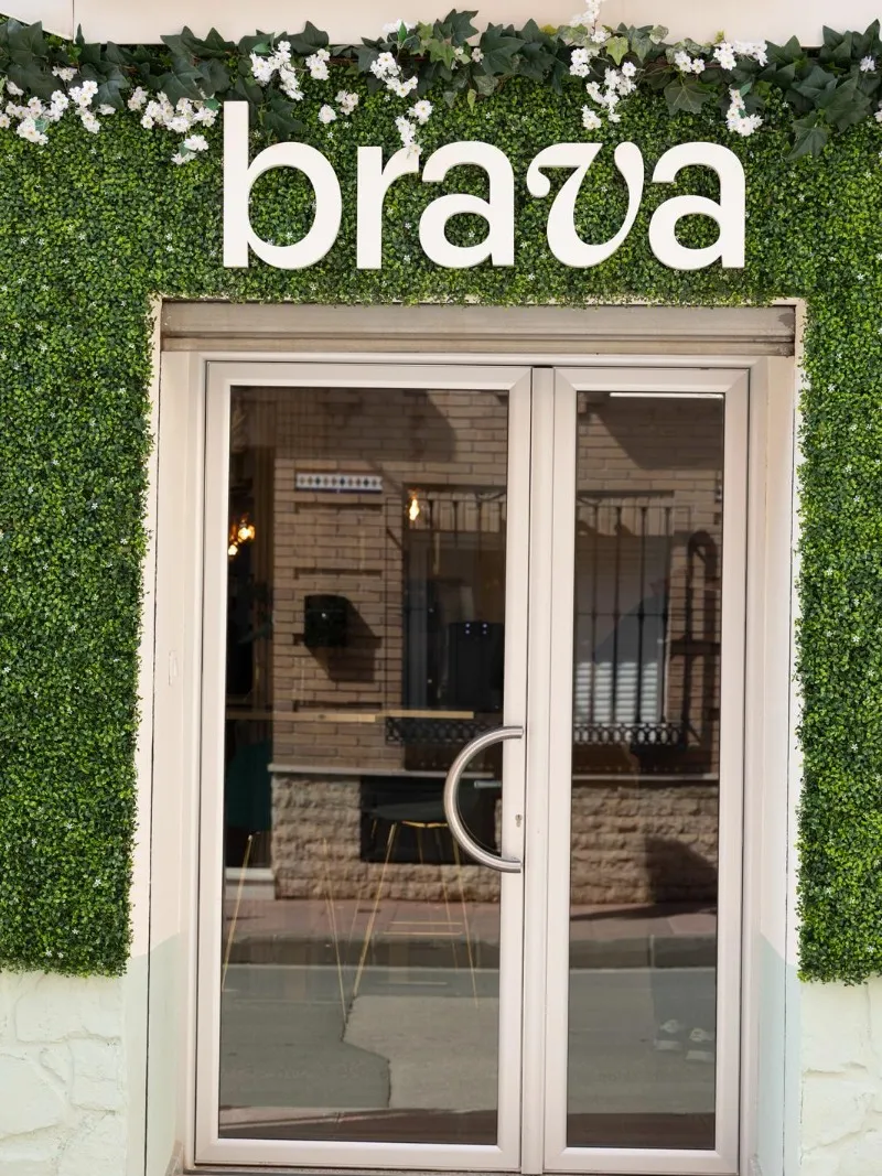 Entrada de Brava con el rótulo brava sobre la pared vegetal y la puerta de cristal en La Ñora, Murcia