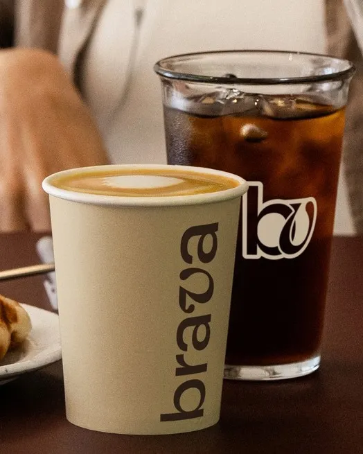 Vaso Brava con café con leche y arte latte junto a un iced coffee y un gofre en Brava
