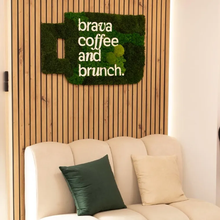 Interior de Brava con el rótulo de musgo brava coffee and brunch y sofá